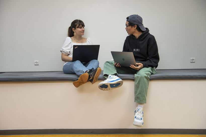 En ung pige og dreng snakker sammen siddende på en bænk